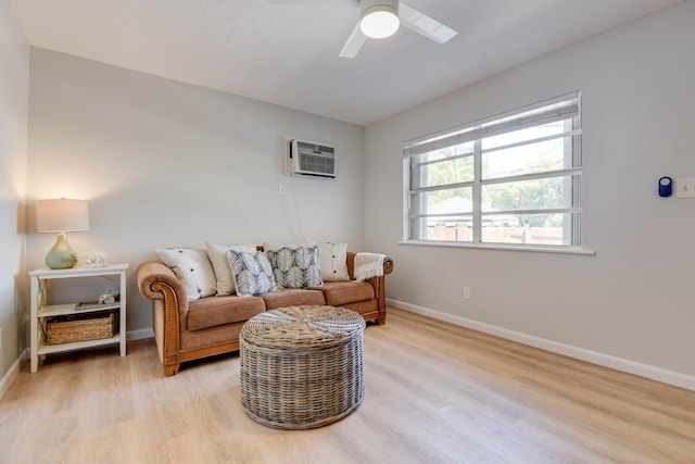 sitting room featuring light hardwood / wood-style floors, an AC wall unit, and ceiling fan