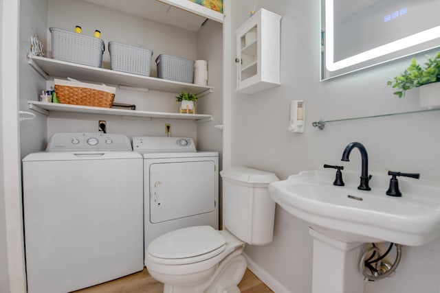 bathroom with independent washer and dryer, wood-type flooring, toilet, and sink