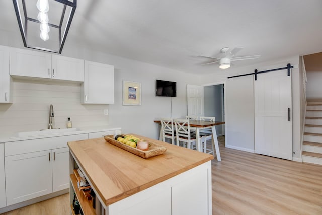 kitchen featuring a barn door, sink, white cabinets, and ceiling fan