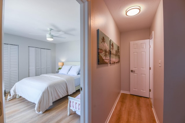 bedroom featuring ceiling fan, two closets, and light wood-type flooring