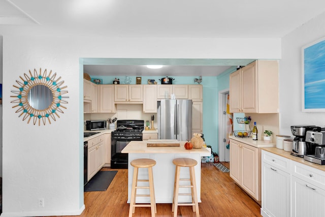 kitchen with a kitchen island, light wood-type flooring, a kitchen breakfast bar, and black appliances