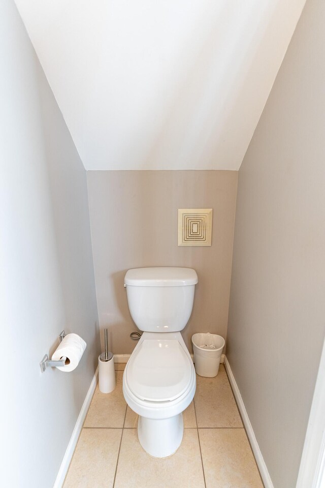 bathroom with tile patterned flooring, vaulted ceiling, and toilet