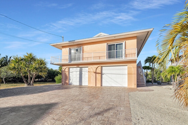 view of property with stucco siding, stairs, decorative driveway, and a balcony