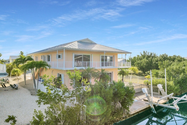 exterior space featuring fence, a standing seam roof, stucco siding, boat lift, and metal roof