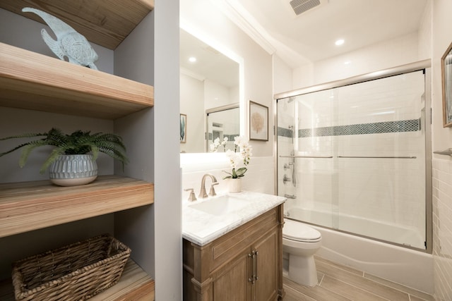 full bathroom with vanity, shower / bath combination with glass door, and toilet