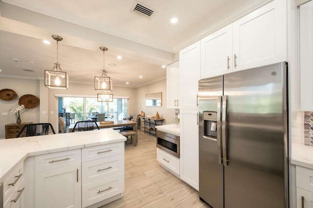 kitchen with light stone counters, hanging light fixtures, white cabinets, and appliances with stainless steel finishes