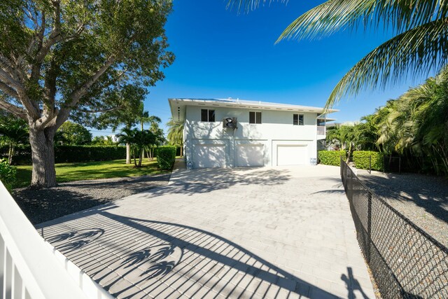 view of front of home with an attached garage, fence, decorative driveway, and stucco siding