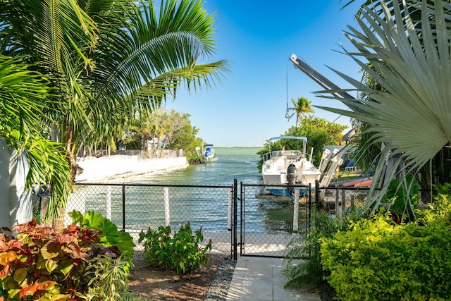 water view with boat lift, a boat dock, fence, and a gate