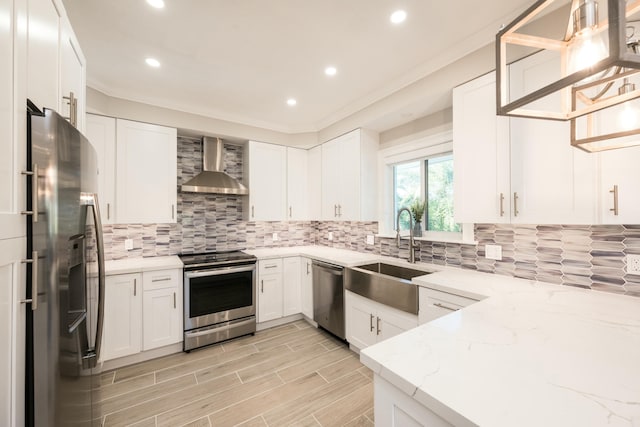 kitchen featuring light stone counters, white cabinetry, stainless steel appliances, and wall chimney range hood