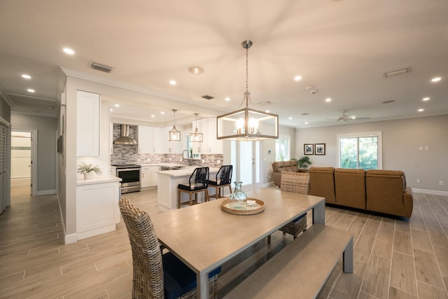 dining room with sink, ceiling fan with notable chandelier, and ornamental molding