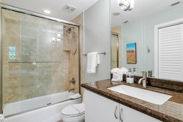 full bathroom with vanity, toilet, and combined bath / shower with glass door