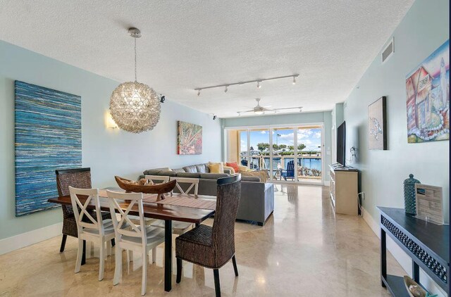 dining room featuring ceiling fan with notable chandelier, track lighting, and a textured ceiling