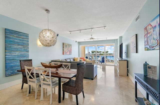 dining room featuring ceiling fan with notable chandelier, track lighting, and a textured ceiling