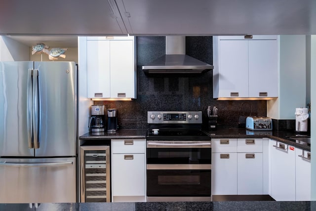 kitchen featuring white cabinetry, dark stone countertops, stainless steel appliances, beverage cooler, and wall chimney exhaust hood