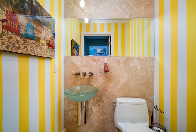 bathroom with sink, tile walls, and toilet