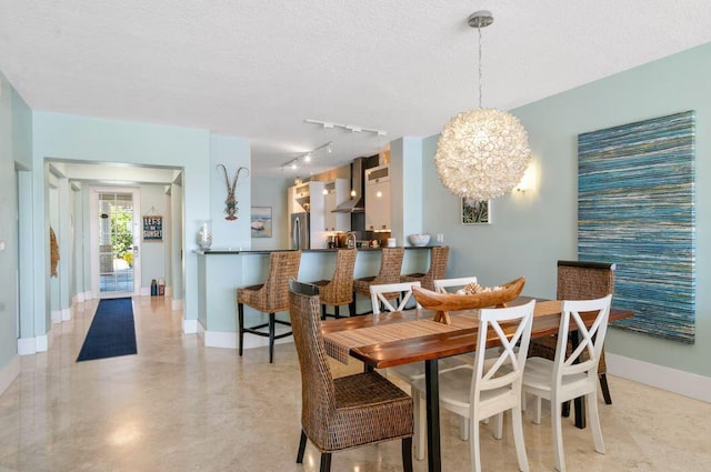 dining space with an inviting chandelier, rail lighting, and a textured ceiling