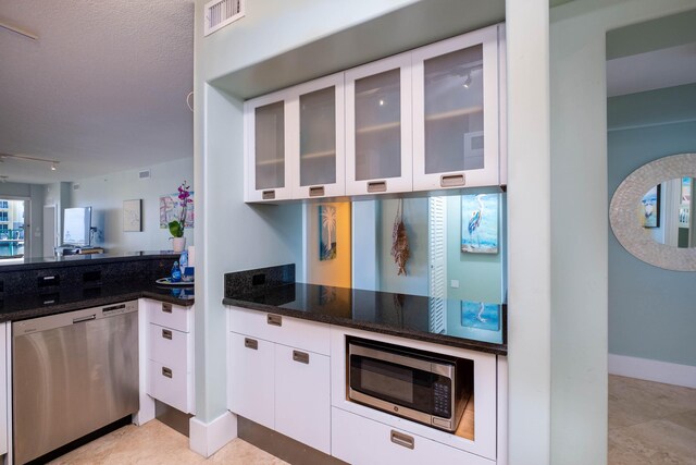 kitchen with dark stone countertops, stainless steel appliances, and white cabinets