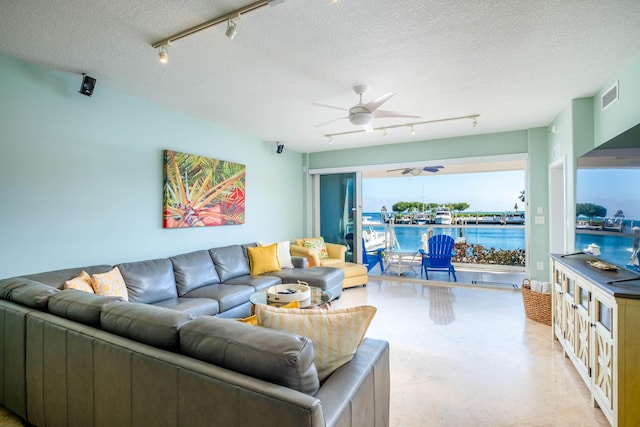 living room featuring ceiling fan and a textured ceiling