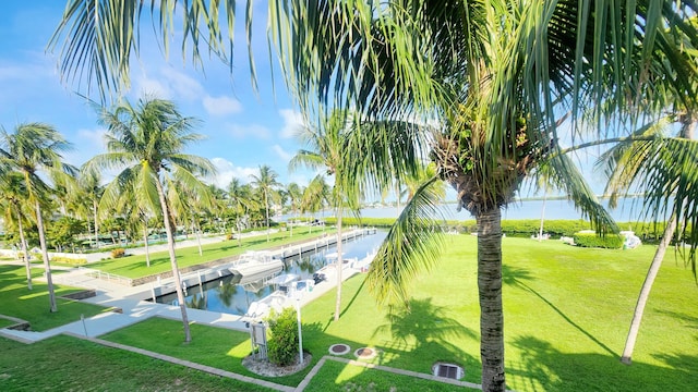 view of community with a dock, a lawn, and a water view