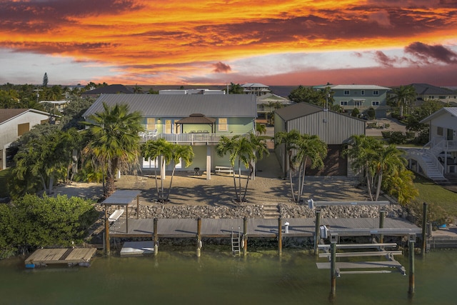 view of dock with a patio area, a water view, boat lift, and a residential view