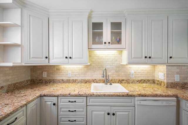 kitchen with sink, light stone counters, white cabinets, and white dishwasher