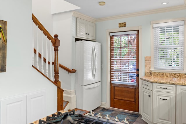 kitchen with white cabinetry, light stone countertops, ornamental molding, and white refrigerator