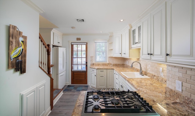 kitchen with sink, white cabinetry, backsplash, light stone countertops, and white fridge