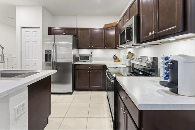 kitchen with dark brown cabinetry, appliances with stainless steel finishes, sink, and light tile patterned floors