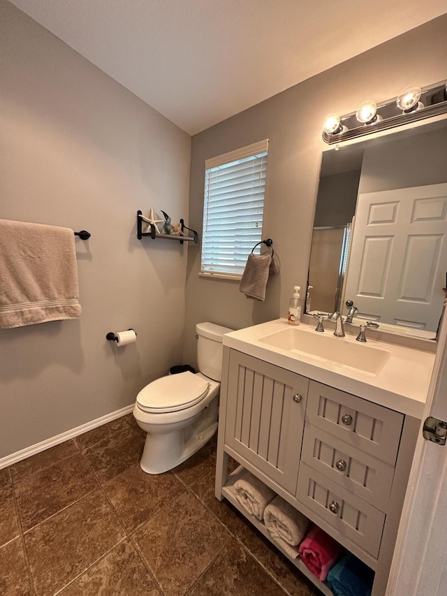 bathroom with a shower with door, vanity, toilet, and baseboards