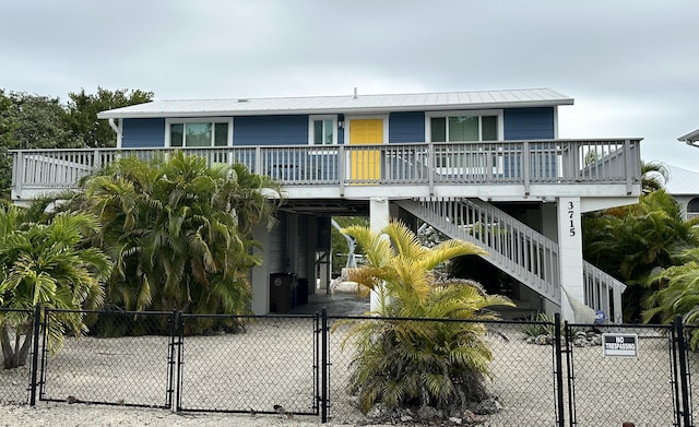 view of front of property with metal roof, a porch, stairway, a gate, and a carport