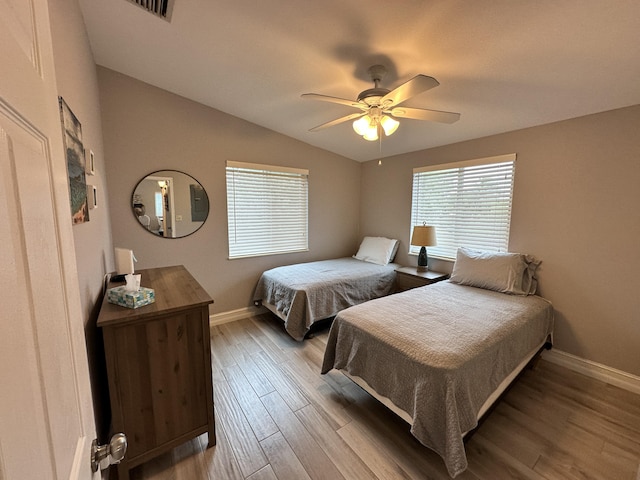 bedroom featuring lofted ceiling, ceiling fan, baseboards, and wood finished floors