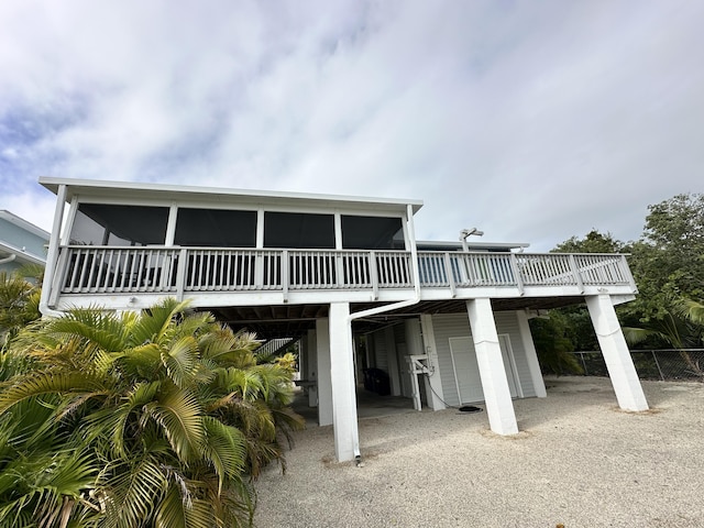 back of house with gravel driveway, a sunroom, a deck, and a carport