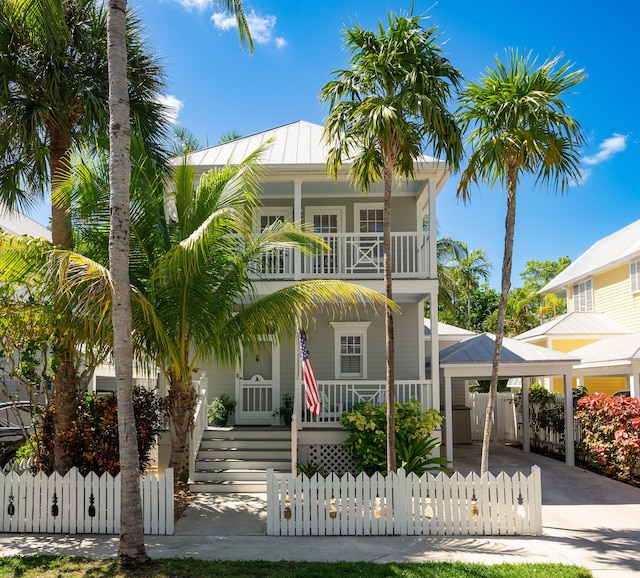 223 Golf Club Dr, Key West, FL 33040 - raised beach house featuring a balcony, a gate, a fenced front yard, covered porch, and a carport