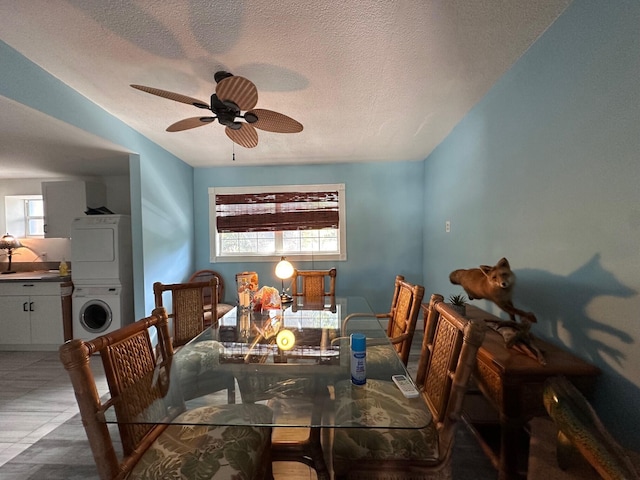 dining room featuring stacked washer / dryer, ceiling fan, and a textured ceiling