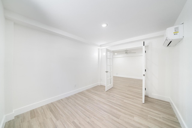 empty room featuring light wood-style flooring, baseboards, an AC wall unit, and recessed lighting