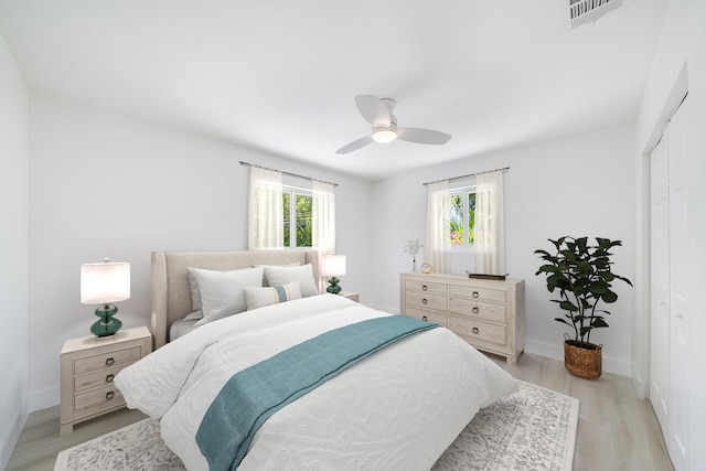 bedroom with visible vents, baseboards, ceiling fan, light wood-style floors, and a closet