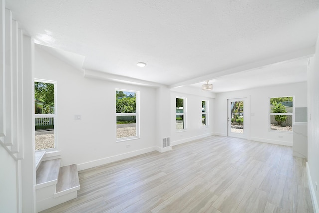 unfurnished living room featuring light wood finished floors, baseboards, visible vents, and a wealth of natural light