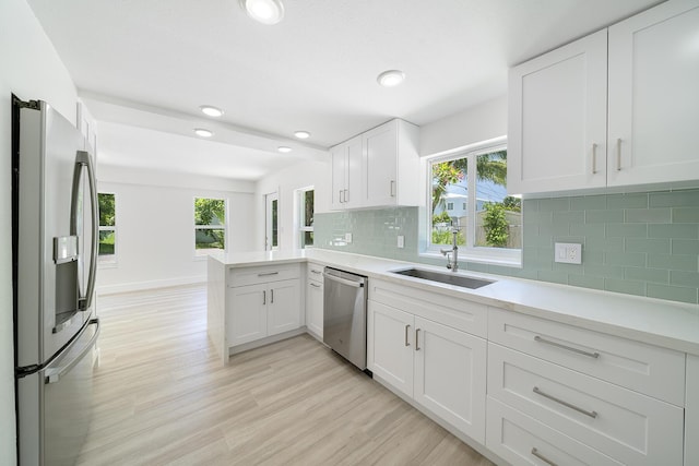 kitchen with stainless steel appliances, a peninsula, light countertops, and white cabinetry