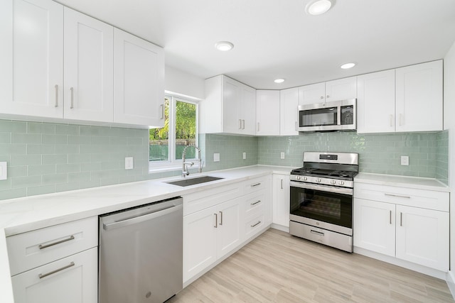 kitchen featuring stainless steel appliances, white cabinetry, and a sink