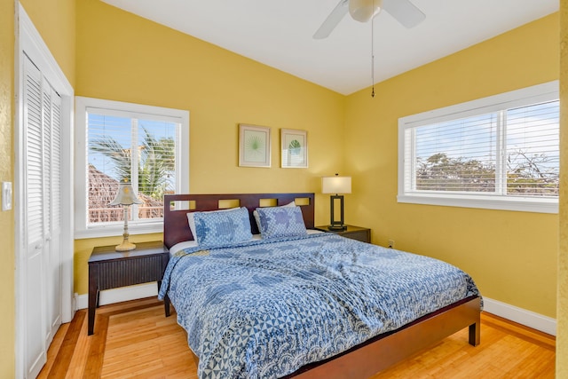 bedroom featuring vaulted ceiling, ceiling fan, light wood-type flooring, and a closet