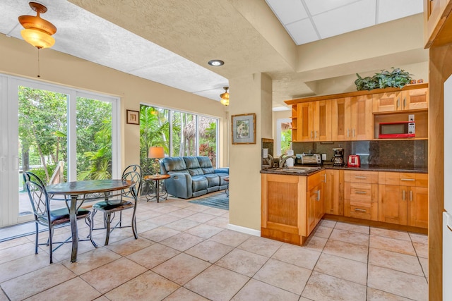 kitchen featuring dark stone countertops, sink, light tile patterned floors, and backsplash