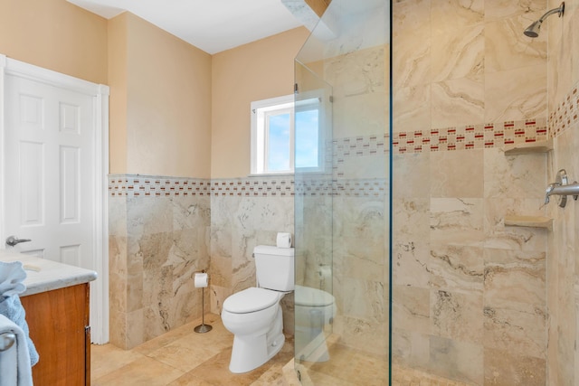 bathroom featuring toilet, tile walls, a tile shower, vanity, and tile patterned flooring