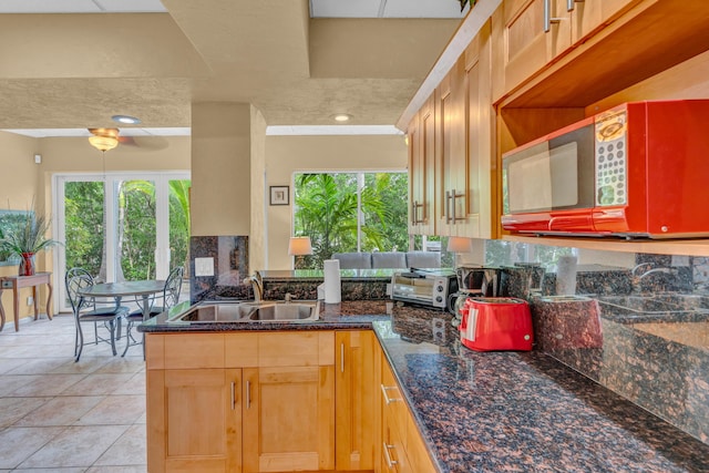 kitchen featuring sink, dark stone countertops, kitchen peninsula, and light tile patterned floors