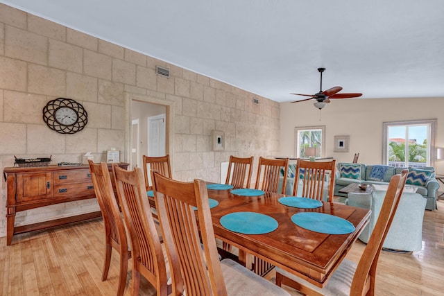 dining area with tile walls, light hardwood / wood-style flooring, and ceiling fan