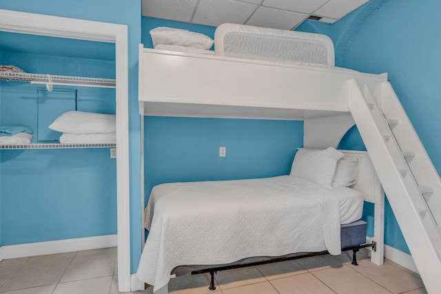 bedroom featuring a drop ceiling and tile patterned floors