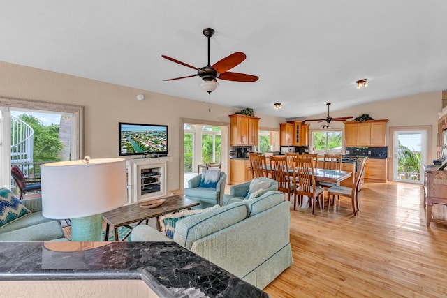 living room with lofted ceiling, ceiling fan, a healthy amount of sunlight, and light wood-type flooring