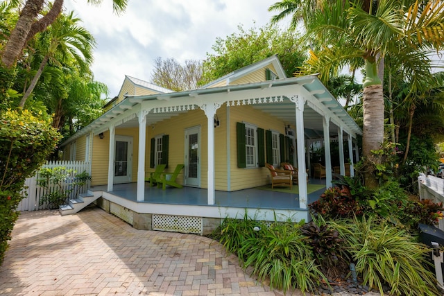 rear view of property featuring crawl space, covered porch, and fence