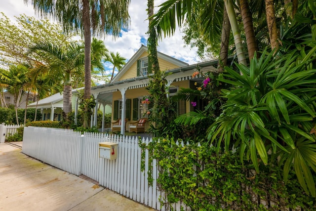 view of side of home featuring covered porch, a fenced front yard, and a gate