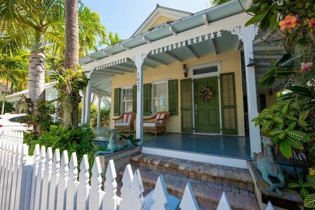 entrance to property featuring a porch and fence