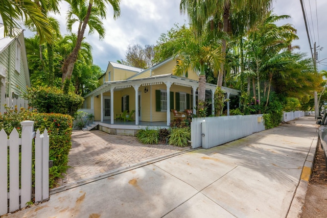 view of front of home with a porch, a fenced front yard, and a gate